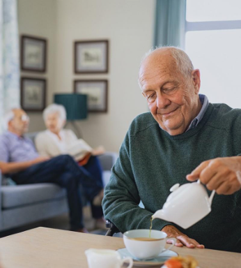 Ein älterer Mann schenkt sich in einem Pflegeheim eine Tasse Tee ein.