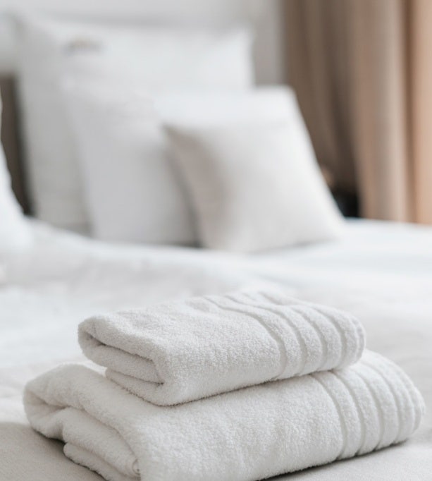 White towels neatly arranged in a contemporary hotel room, promoting Avendra International's luxury hospitality solutions.