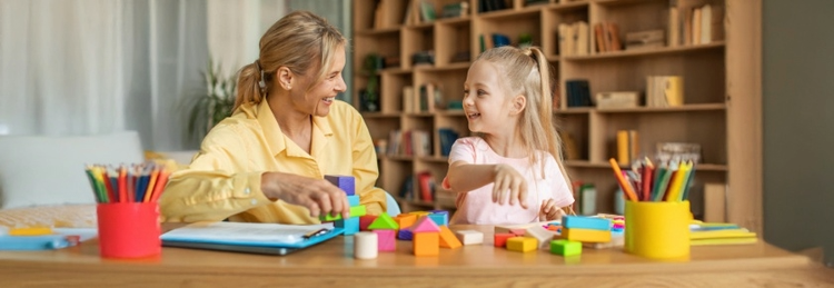 A woman and a child joyfully playing together, building structures with colorful blocks