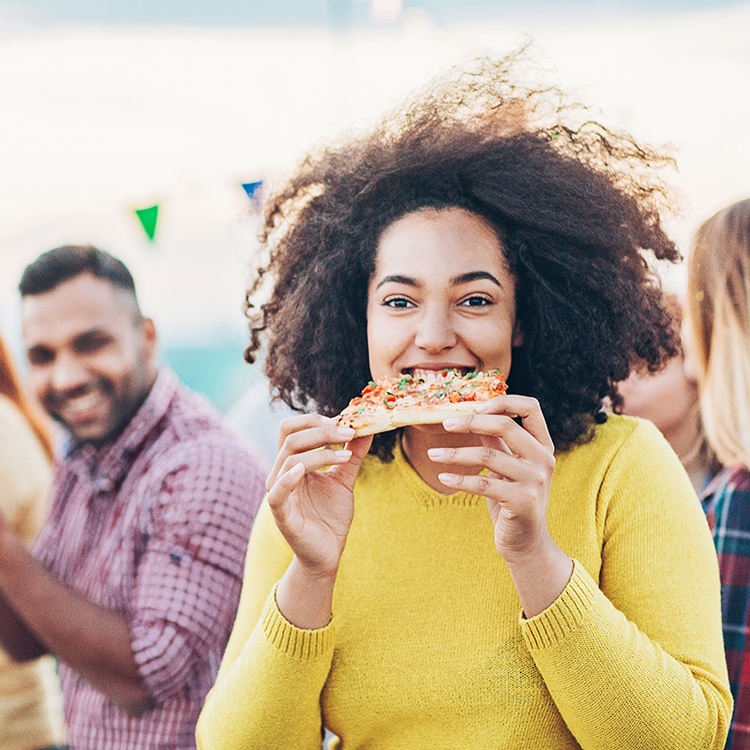 Foodservice consumer enjoying pizza at a social dining event, representing emerging culinary trends, menu innovation and changing dining preferences in 2026.