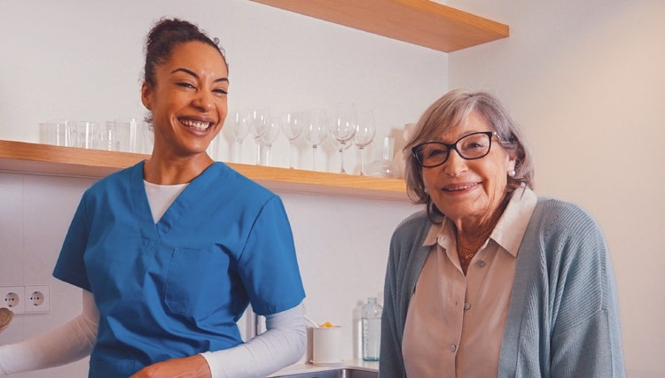 Smiling healthcare worker assisting an elderly resident in a care home kitchen, illustrating high-quality support services and compassionate healthcare hospitality.