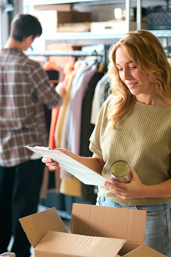 Woman reviews the contents on her cliipboard in front of a rack of clothes
