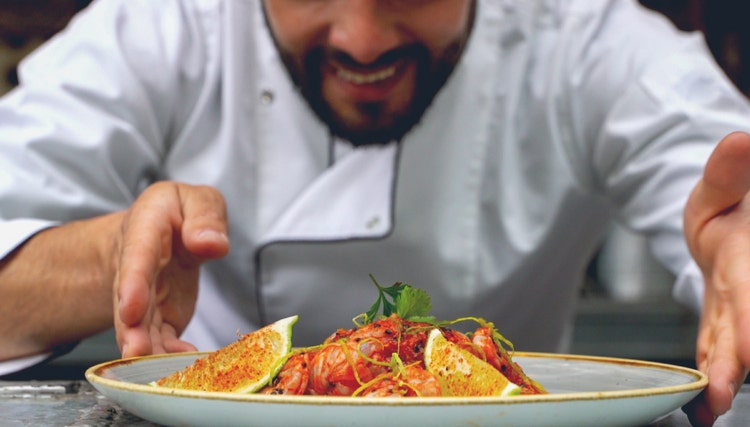 Professional chef plating a gourmet dish in a restaurant kitchen, highlighting culinary expertise and premium food and beverage service in the hospitality sector.