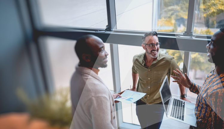 Three male colleagues conversing by a large window