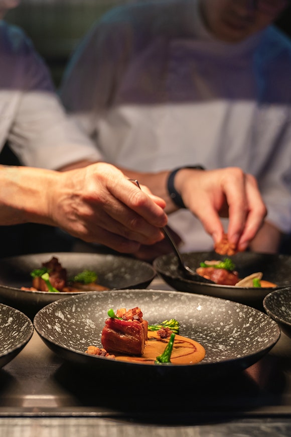 Chef plating and garnishing a steak dish