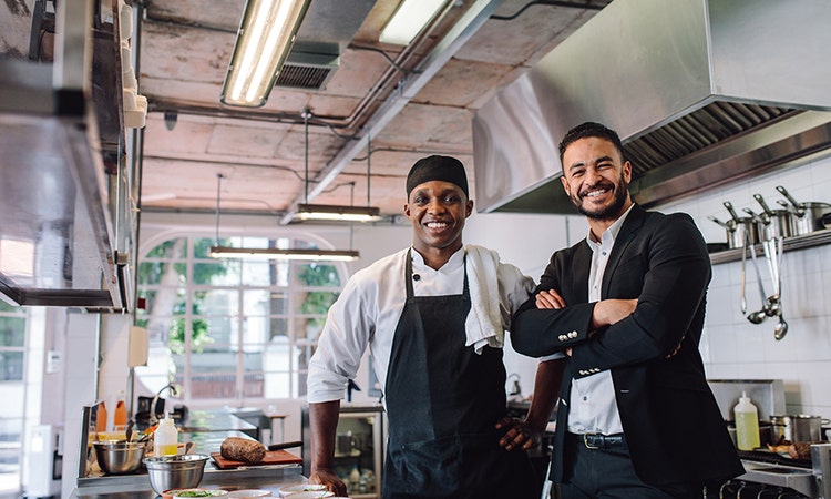 Chef and manager posing with a smile in a commercial kitchen