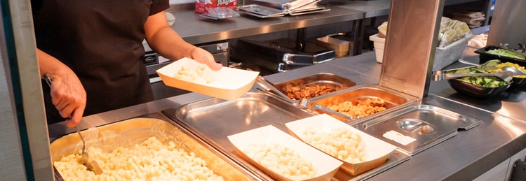 Scooping pasta into a dish at a school canteen