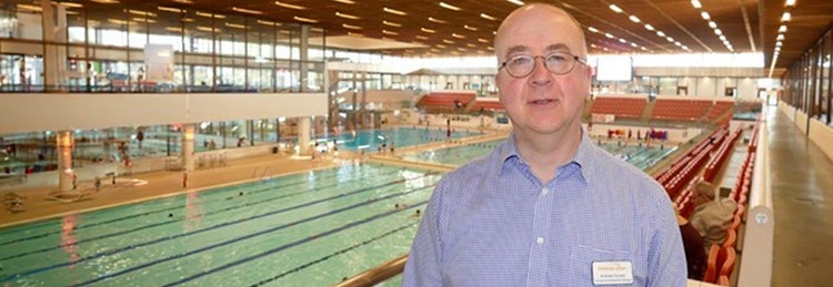 Man with name tag standing in front of swimming pool
