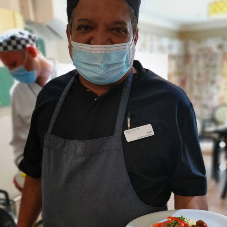 Chef with plate of food wearing a mask