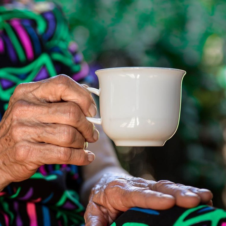 An elderly woman enjoying a warm cup of coffee