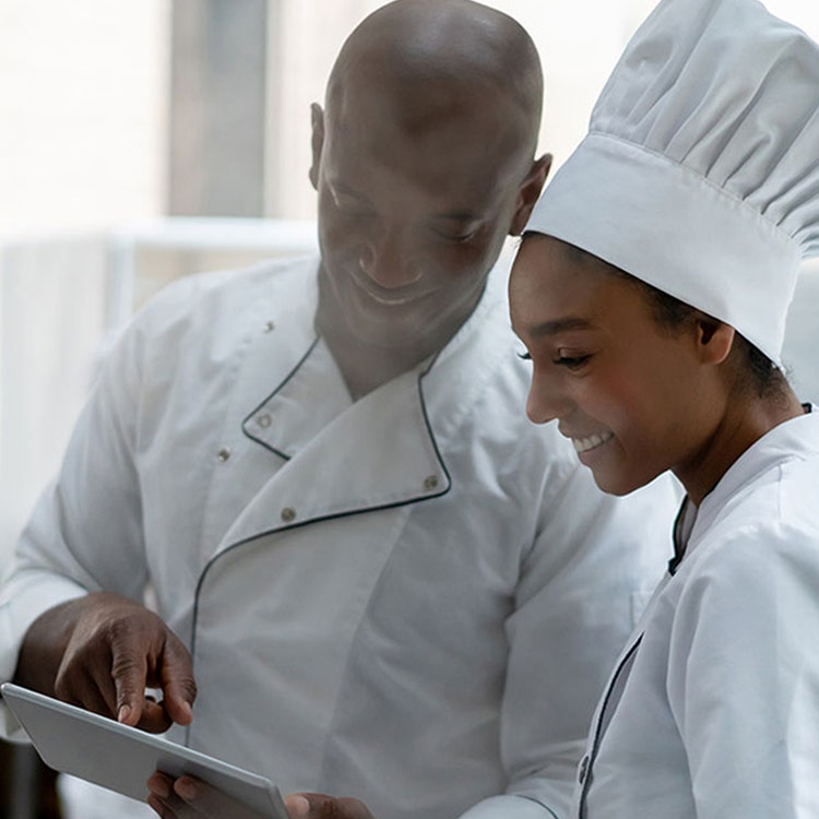Close up of chefs smiling staring at a tablet