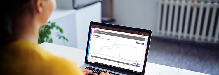 A woman looking at a laptop screen, displaying a line graph.