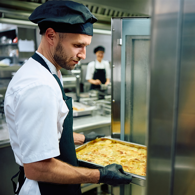 Professional chef preparing a freshly cooked meal in a commercial school catering kitchen.