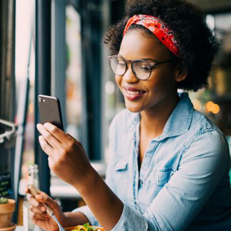 A woman at her phone while enjoying a fresh salad