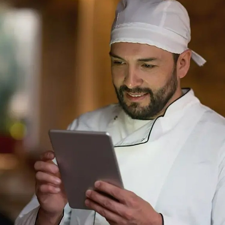 A chef using a tablet to view dietary requirements