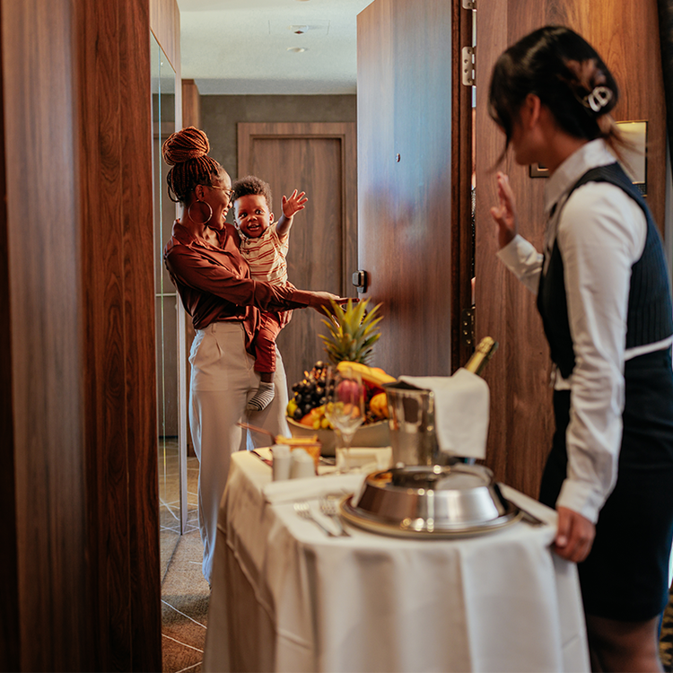Hotel staff welcoming a parent and child to their room with personalised amenities