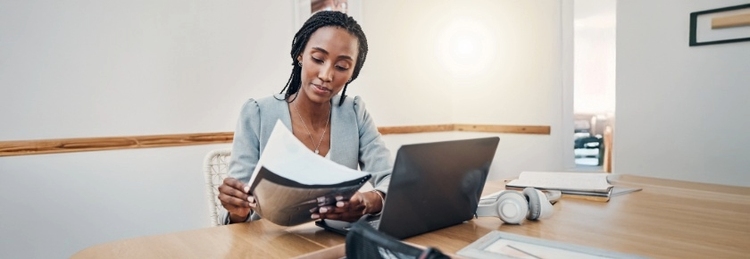 Procurement professional reviewing contract documents alongside a laptop