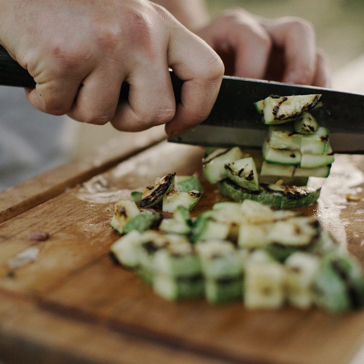 A person chopping fresh cucumbers