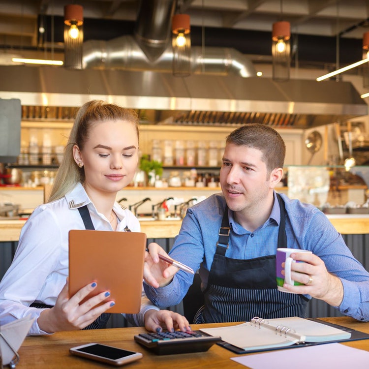 Two Caterers seated engaged with a tablet