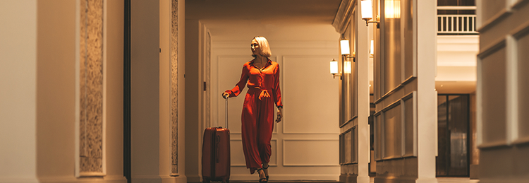Guest walking through a luxury hotel corridor with her suitcase