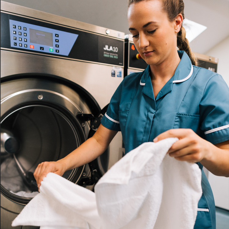 woman washing towels at laundry machine