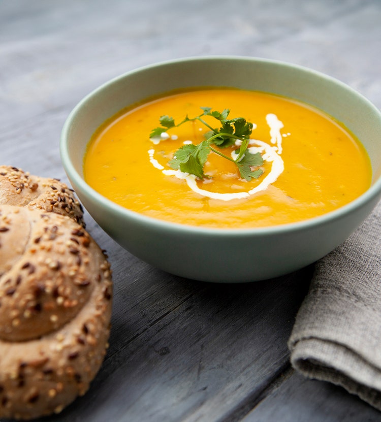 Bowl of orange soup and a baked good