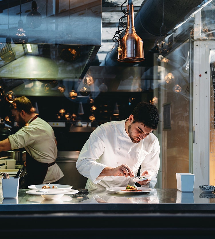 Chefs plating and garnishing dishes in a commercial kitchen