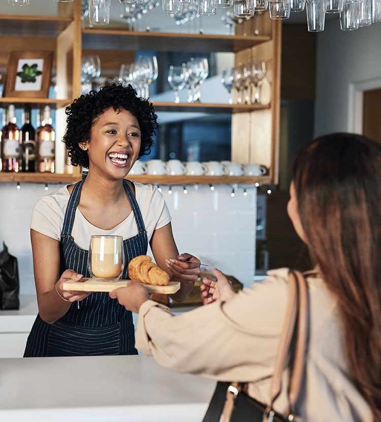Restaurant server handing a drink and food order to a customer