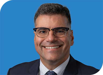 A professional headshot of Leonard Queiroz with a blue background