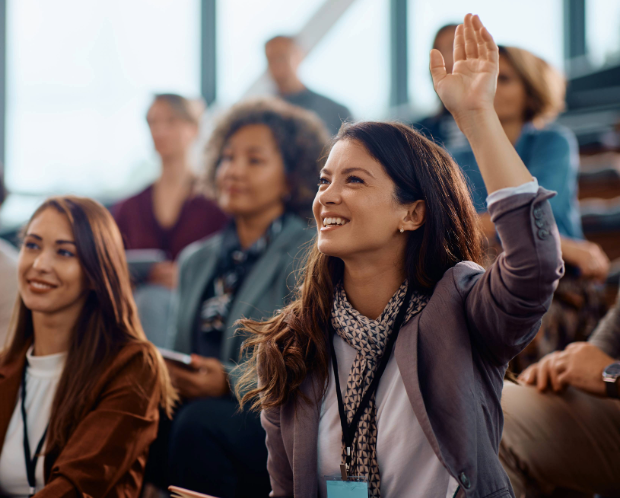 Happy entrepreneur raising her hand to answer a question at Avendra International, engaged and knowledgeable team members