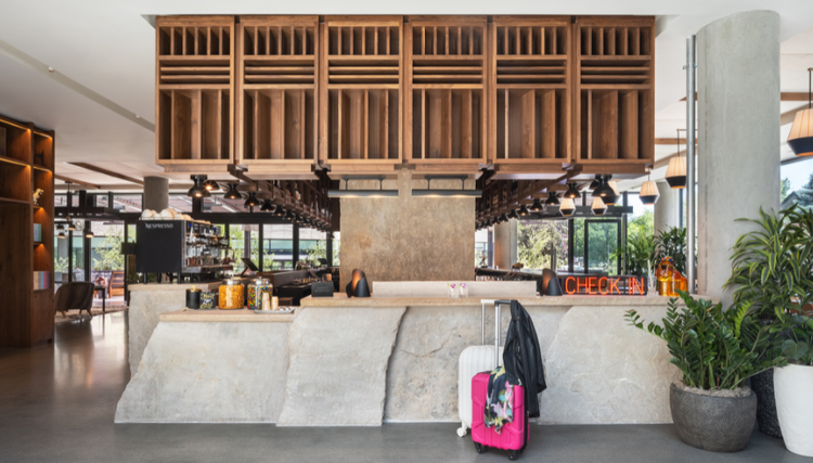 Modern hotel front desk and lounge with wooden cabinetry.