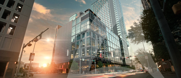 A glass skyscraper in a busy city at sunset.