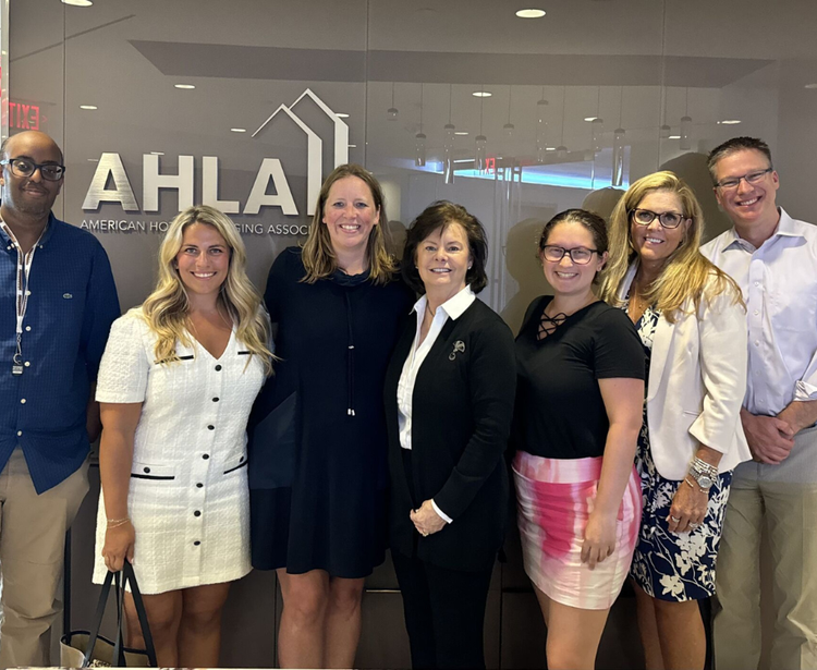 A group of people standing in front of a wall displaying the logo and name of the American Hotel & Lodging Association, suggesting a professional or networking event.