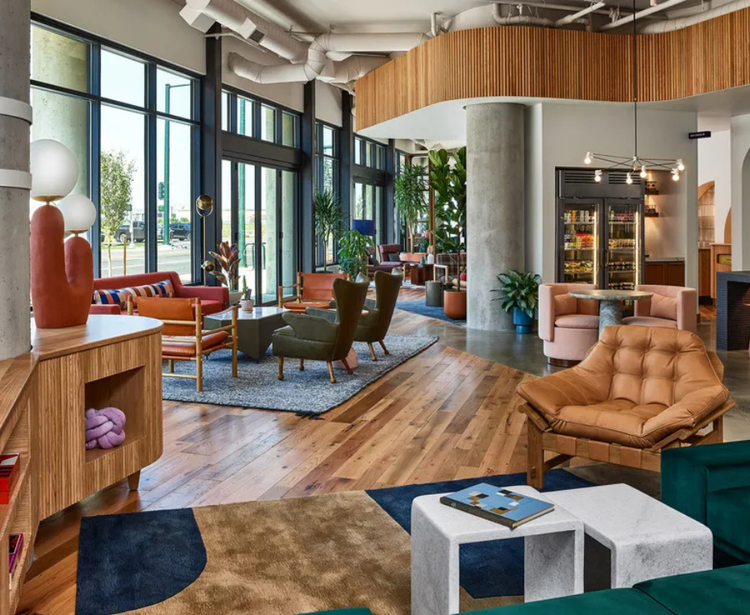 A stylish lounge with modern seating, wood flooring, and natural light.
