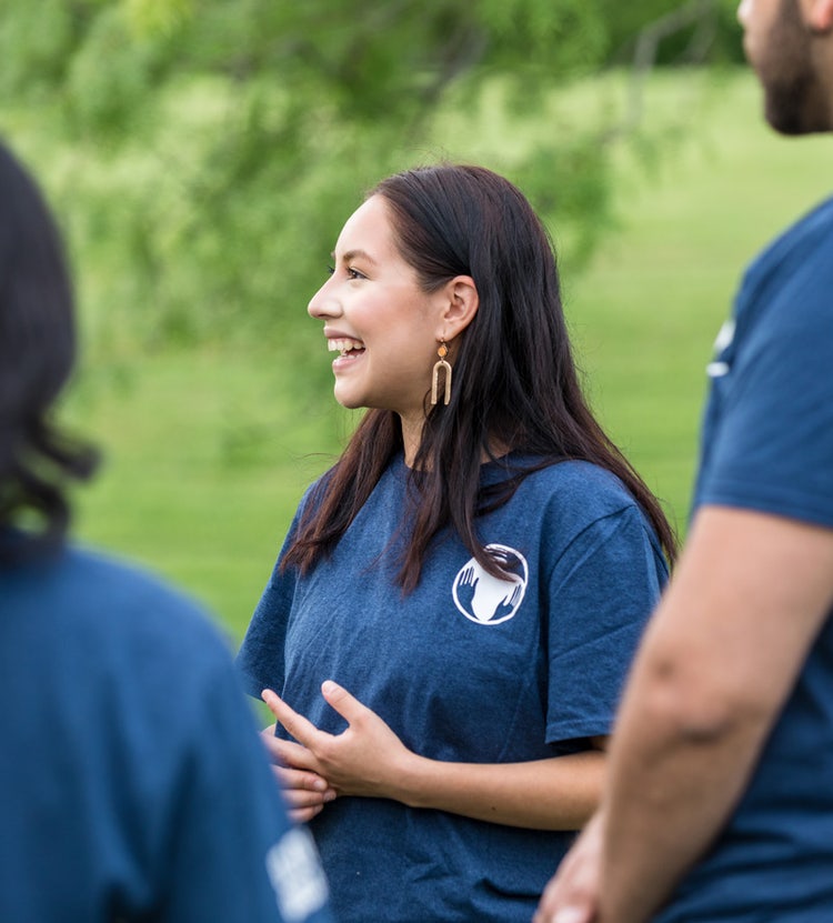Young adult female smiling while listening to a presentation at Avendra International, responsible sourcing and employee engagement