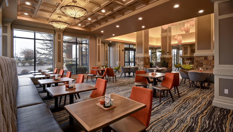Hotel lobby featuring a spacious dining area with elegant furnishings and large windows allowing natural light.