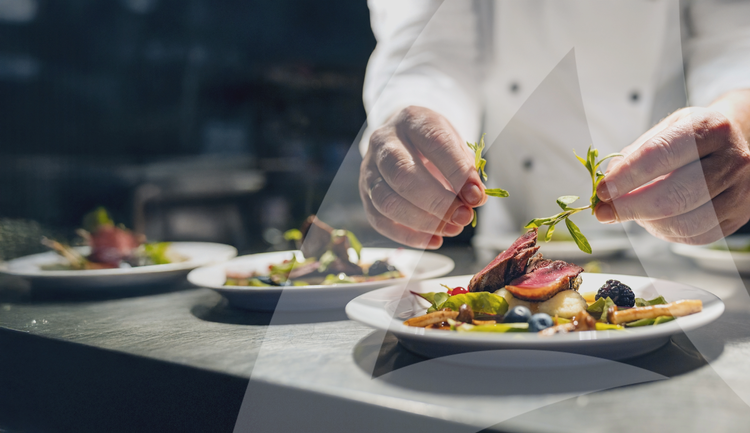 Chef plating and garnishing a steak dish