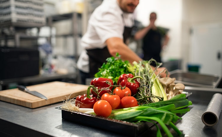 Assortment of fresh vegetables with chefs in the background