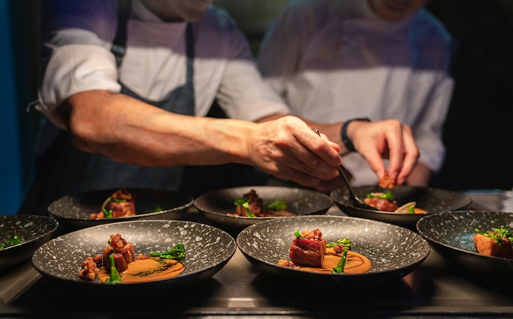 Chef plating and garnishing a steak dish