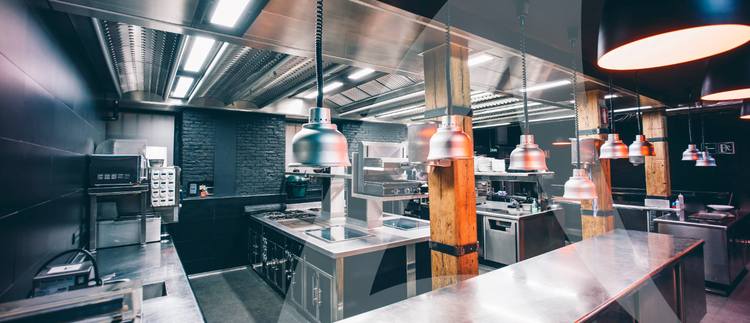 A modern kitchen featuring stainless steel countertops and bright overhead lights.