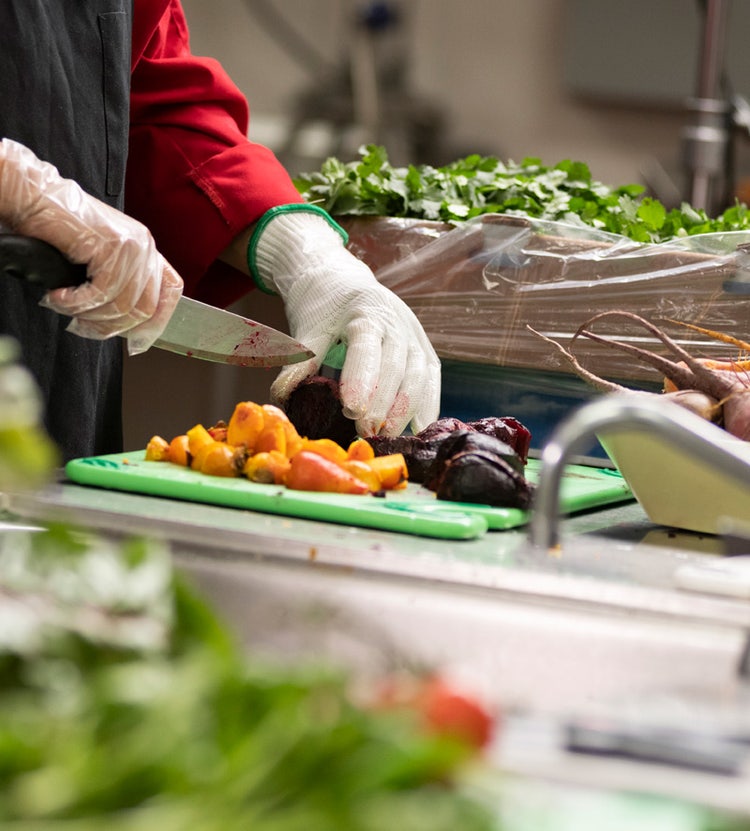 Chef wearing a cut glove while preparing food at Avendra International, kitchen safety and hygiene