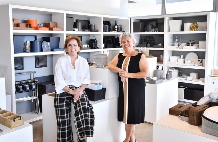 OH Worldwide owners, two women smiling in front of dishware