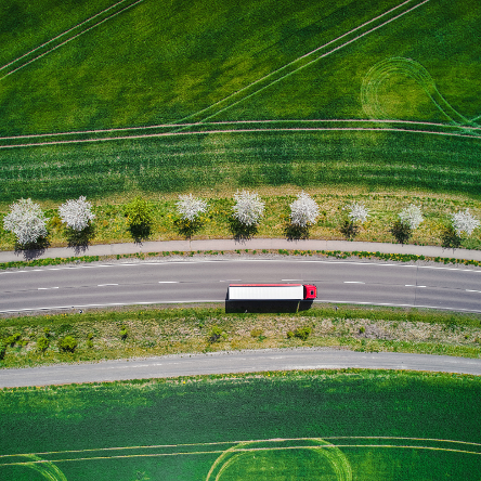 Aerial view of a truck on a road surrounded by grass