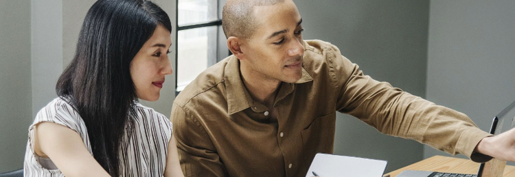 A woman and man working together and looking at laptops