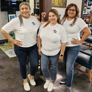 hree women smiling wearing white Corporate Building Services Inc shirts