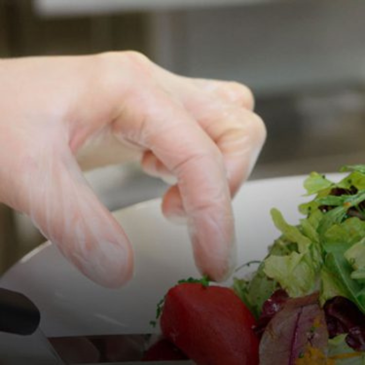Hand in glove reaching for a strawberry