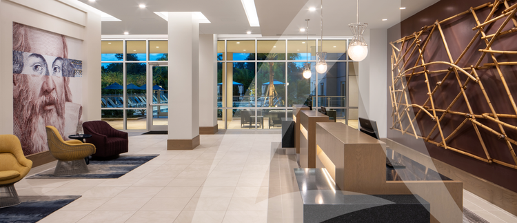 A modern hotel lobby with a reception desk, stylish seating, featuring warm lighting and contemporary decor.