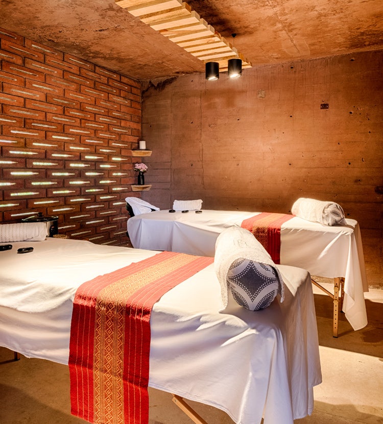 Massage tables with hot basalt lava stones in a spa room - Avendra International's premium wellness services