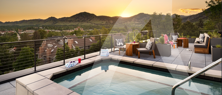 A rooftop terrace with a swimming pool, modern outdoor furniture, and a scenic mountain view at sunset.