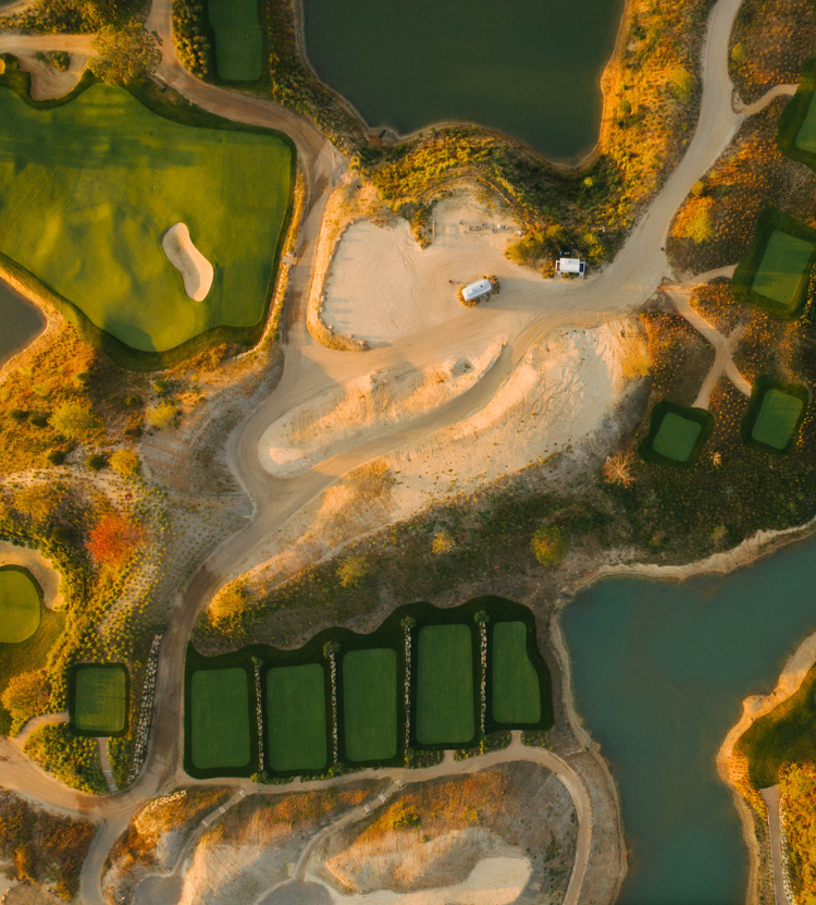 An aerial view of a golf course highlighting its turf management, including fairways, bunkers, water features, and maintained greens.